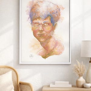 May include: Watercolor portrait of a person in a white frame. The artwork features a face with a stern expression, rendered in shades of yellow, pink, and blue. The painting is displayed on a white wall above a wooden cabinet.