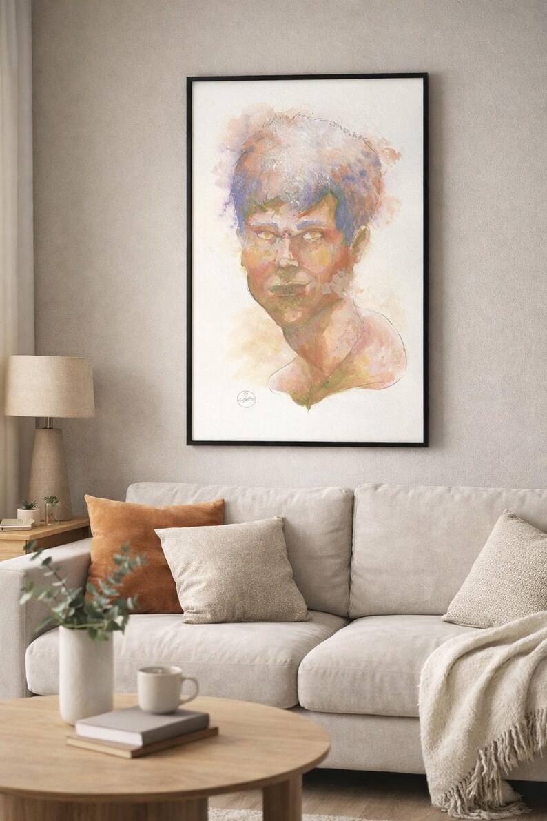 May include: A framed watercolor portrait of a person with blue and orange hair. The artwork is displayed above a light-colored sofa with decorative pillows. A wooden coffee table and a lamp are in the foreground.