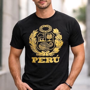 Peut inclure: T-shirt noir à col rond avec un emblème doré du Pérou. L'emblème présente un bouclier avec un vigogne, un arbre de quinquina et une corne d'abondance, entouré de branches de laurier et le mot "PERÚ".