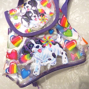 May include: Clear plastic tote bag with a purple trim and handle. The bag features colorful cartoon images of dogs, hearts, and pinwheels. The Lisa Frank logo is visible on the bag.