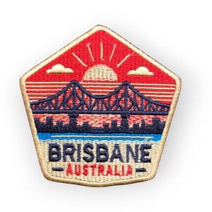 May include: Embroidered patch featuring a bridge over water with a cityscape silhouette. The patch has a red background with a rising sun and the text "BRISBANE - AUSTRALIA" in blue and white.