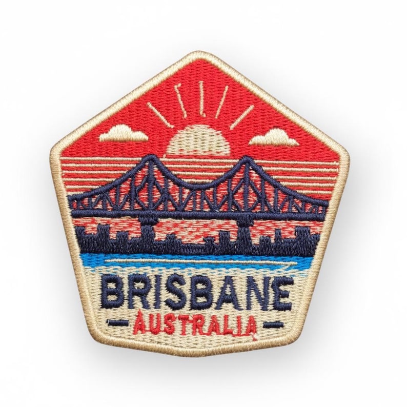 May include: Embroidered patch featuring a bridge over water with a sunset design. The patch is in a pentagon shape with the words "BRISBANE AUSTRALIA" at the bottom. The patch has red, blue, and beige colors.
