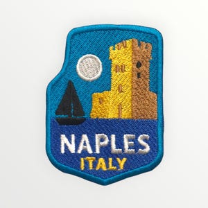 Può includere: Toppa ricamata raffigurante una scena costiera con una barca a vela, un castello e una luna piena su uno sfondo blu. La toppa recita "NAPLES ITALY" in lettere bianche e gialle, con un bordo blu.