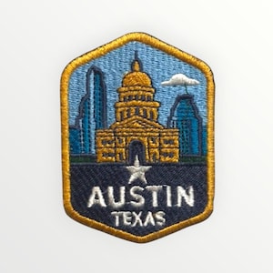 Puede incluir: Parche bordado con el horizonte de Austin, Texas. El diseño incluye el edificio del Capitolio estatal, una estrella y el texto "AUSTIN TEXAS" en blanco sobre un fondo azul marino, enmarcado por un borde dorado.