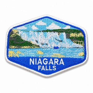 May include: A hexagonal embroidered patch featuring a landscape of Niagara Falls with white water cascading over a cliff, green foliage, and blue sky with white clouds. The text NIAGARA FALLS is stitched in white capital letters at the bottom.