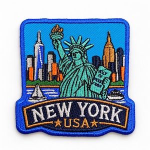 Puede incluir: Un parche bordado rectangular que muestra la Estatua de la Libertad en color verde azulado, sosteniendo una antorcha y una tableta, sobre un horizonte de Nueva York con edificios naranjas y azules. La banda inferior muestra NEW YORK USA.