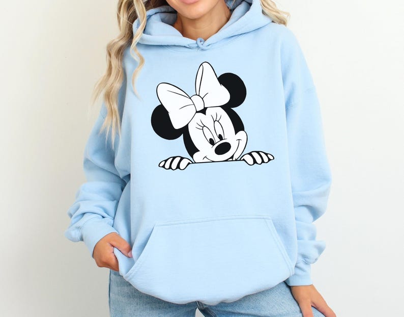 May include: Light blue hoodie featuring a black and white Minnie Mouse graphic. The graphic shows Minnie Mouse's face, bow, and hands. The hoodie has a front pocket and a drawstring hood.