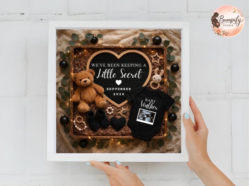 Pu&ograve; includere: Annuncio incorniciato con un cartello a forma di cuore che recita "We've Been Keeping a Little Secret September 2026". Il display include un orsacchiotto, vestiti per bambini, stivaletti e un'immagine ecografica. La cornice &egrave; bianca.
