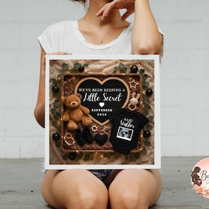 Square wicker basket pregnancy announcement with heart letter board reading “We’re Expecting Little Miracle December 2024,” featuring black baby onesie, black booties, brown teddy bear, soft fur lining, neutral fabric background, and warm fairy lights.