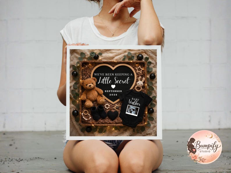 Square wicker basket pregnancy announcement with heart letter board reading “We’re Expecting Little Miracle December 2024,” featuring black baby onesie, black booties, brown teddy bear, soft fur lining, neutral fabric background, and warm fairy lights.