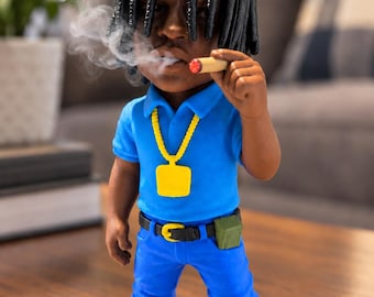 May include: A figurine with black dreadlocks wearing a bright blue polo shirt, blue pants, a yellow chain necklace, and white sneakers. The figure holds a cigar with visible smoke and has a small green pouch attached to a black belt.