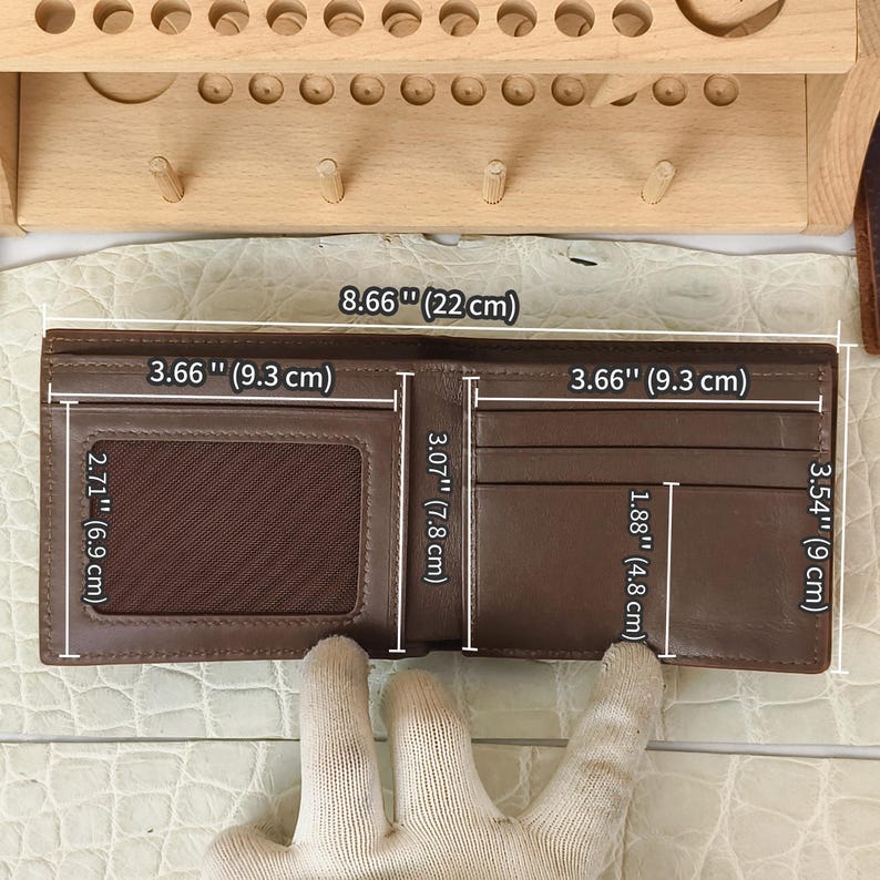 Puede incluir: Una cartera bifold de cuero marr&oacute;n con una ventana transparente para identificaci&oacute;n y m&uacute;ltiples ranuras para tarjetas. La cartera mide 22 cm de ancho por 9 cm de alto abierta, con secciones internas de 9,3 cm por 7,8 cm y 6,9 cm por 4,8 cm.