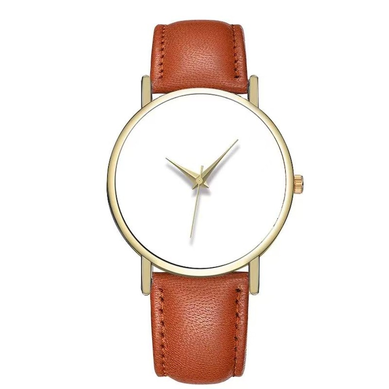 May include: A minimalist wristwatch with a gold-tone case and a white watch face. The watch features gold hands and a brown leather band. The watch is a classic design, suitable for everyday wear.