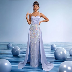 May include: A light purple formal gown with spaghetti straps and a flowing train. The bodice has a sweetheart neckline, and the skirt is embellished with floral embroidery and sequins. The dress is suitable for special occasions.