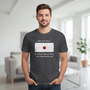 May include: Dark gray t-shirt with a white envelope graphic sealed with a red wax stamp. The text on the shirt reads, "Wear this shirt. Best shirt wearer wins. Your time starts now."
