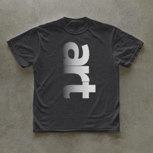 May include: A charcoal gray short-sleeve t-shirt featuring the word art printed vertically in a white, textured, gradient font across the center of the chest. The garment has a standard crew neckline and a straight hemline design.