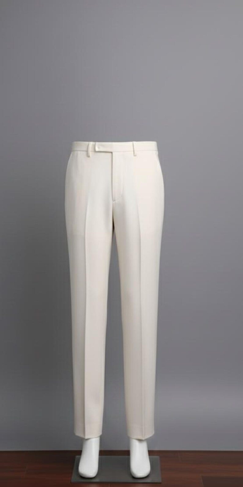 May include: Cream-colored dress pants with a straight leg design. The pants have a waistband with belt loops and a button closure. The fabric appears to be a smooth, woven material. The pants are displayed on a mannequin.