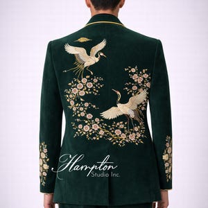 May include: Dark green velvet suit with gold trim and embroidered crane and floral design. The back of the jacket features two cranes with outstretched wings, surrounded by delicate flowers. The suit is from Hampton Studio Inc.