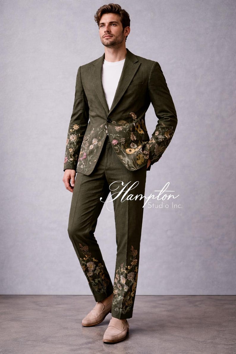 May include: Olive green suit with floral embroidery on the jacket sleeves and pant legs. The suit is paired with a white t-shirt and tan loafers. The text "Hampton Studio Inc." is visible on the pants.
