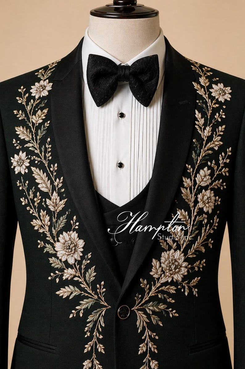 May include: Black tuxedo jacket with floral embroidery in gold and cream. The jacket features a black bow tie, a white dress shirt, and a black vest. The Hampton Studio Inc. logo is visible on the vest.
