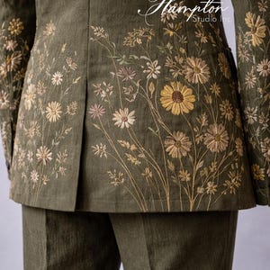May include: Olive green suit jacket and pants with floral embroidery. The jacket features detailed embroidery of daisies and other wildflowers in shades of yellow, tan, and pink. The Hampton Studio Inc. logo is visible.