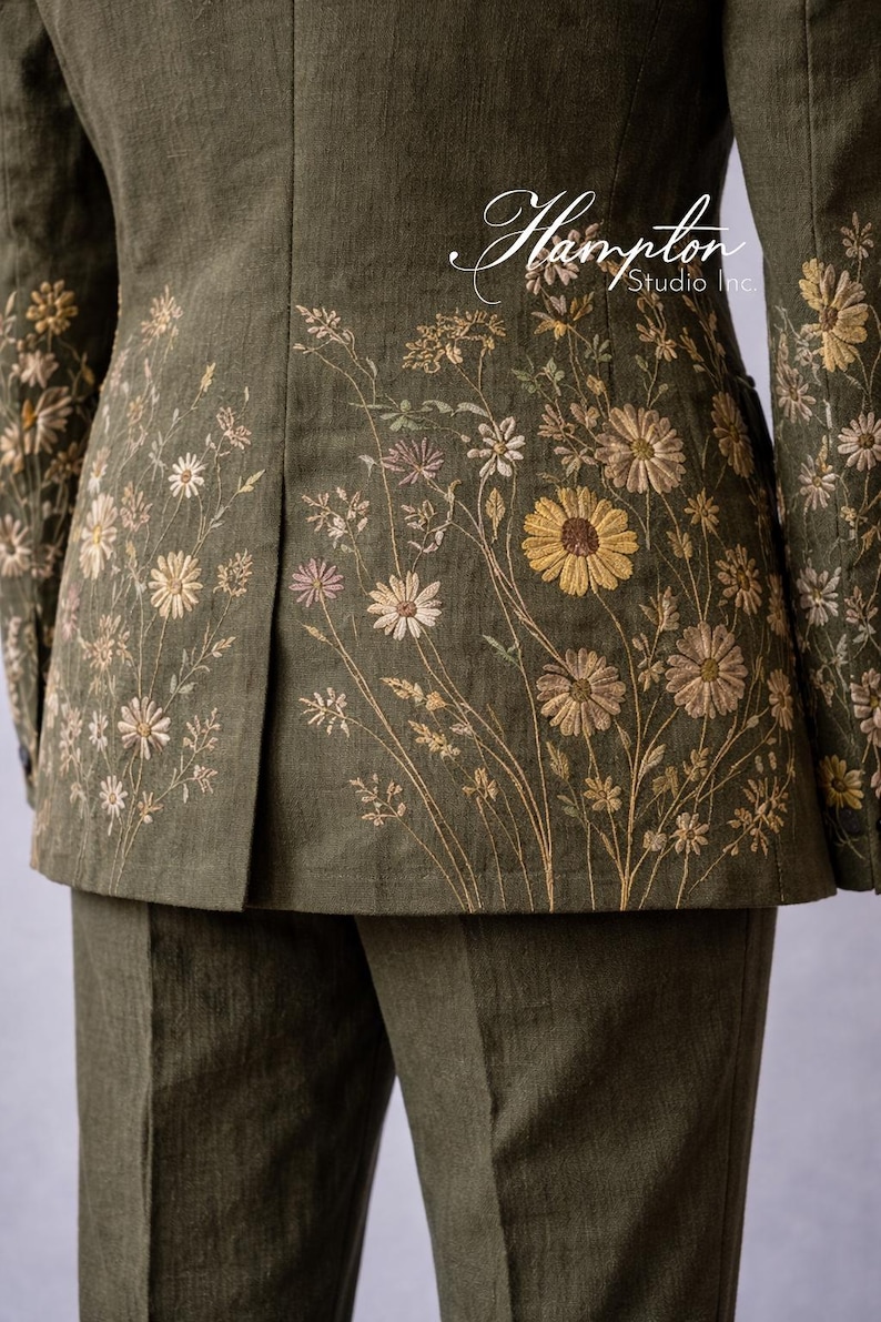 May include: Olive green suit jacket and pants with floral embroidery. The jacket features detailed embroidery of daisies and other wildflowers in shades of yellow, tan, and pink. The Hampton Studio Inc. logo is visible.