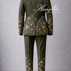 May include: Olive green suit with floral embroidery. The jacket and pants feature detailed embroidery of wildflowers in shades of yellow, cream, and brown. The suit is displayed on a mannequin. The text "Hampton Studio Inc." is visible.