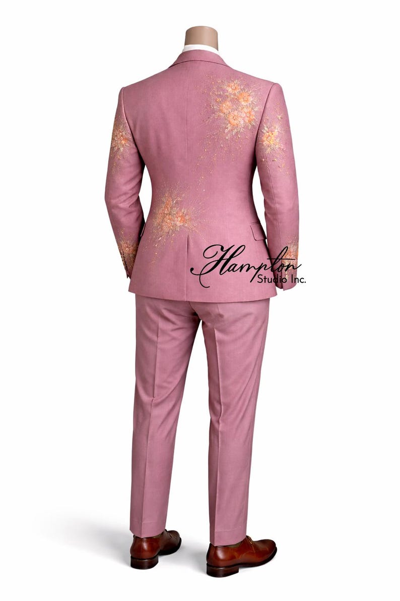 K&ouml;nnte beinhalten: Ein staubrosa Anzug mit floralen Stickereien an den &Auml;rmeln und am R&uuml;cken der Jacke. Der Anzug besteht aus einer Zweiknopfjacke und einer passenden Hose. Das Bild zeigt die R&uuml;ckseite des Anzugs mit dem Text "Hampton Studio Inc.".