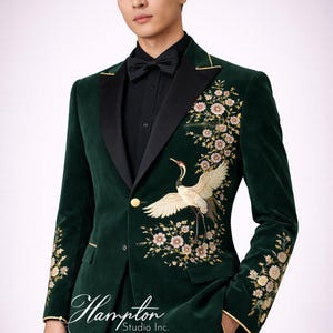 May include: A dark green velvet suit with a black satin lapel and gold trim. The suit features an embroidered crane and floral design on the front and sleeves. The suit includes a matching bow tie and a black dress shirt. The Hampton Studio Inc. logo is visible.