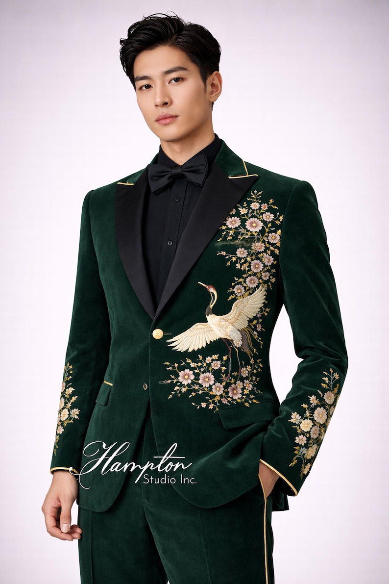 May include: A dark green velvet suit with a black satin lapel and gold trim. The suit features an embroidered crane and floral design on the front and sleeves. The suit includes a matching bow tie and a black dress shirt. The Hampton Studio Inc. logo is visible.