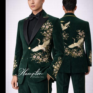 May include: Emerald green velvet suit with floral and crane embroidery. The suit features a black satin lapel, gold trim, and a single-button closure. The image includes the text "Hampton Studio Inc."