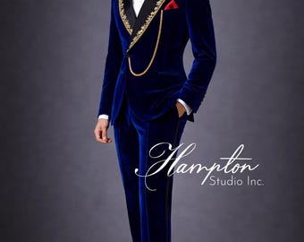 May include: A formal blue velvet suit with gold embroidery on the lapels and a red pocket square. The suit includes a matching jacket and pants. A gold chain hangs from the lapel. The suit is paired with a black bow tie and dress shoes.