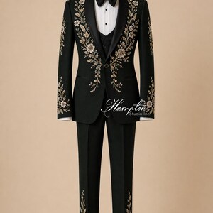 May include: A dark green formal suit with floral embroidery. The suit includes a blazer, vest, and trousers, displayed on a mannequin. The blazer features black lapels, a black bow tie, and white shirt. The floral embroidery is gold and cream-colored. The text "Hampton Studio Inc" is visible.