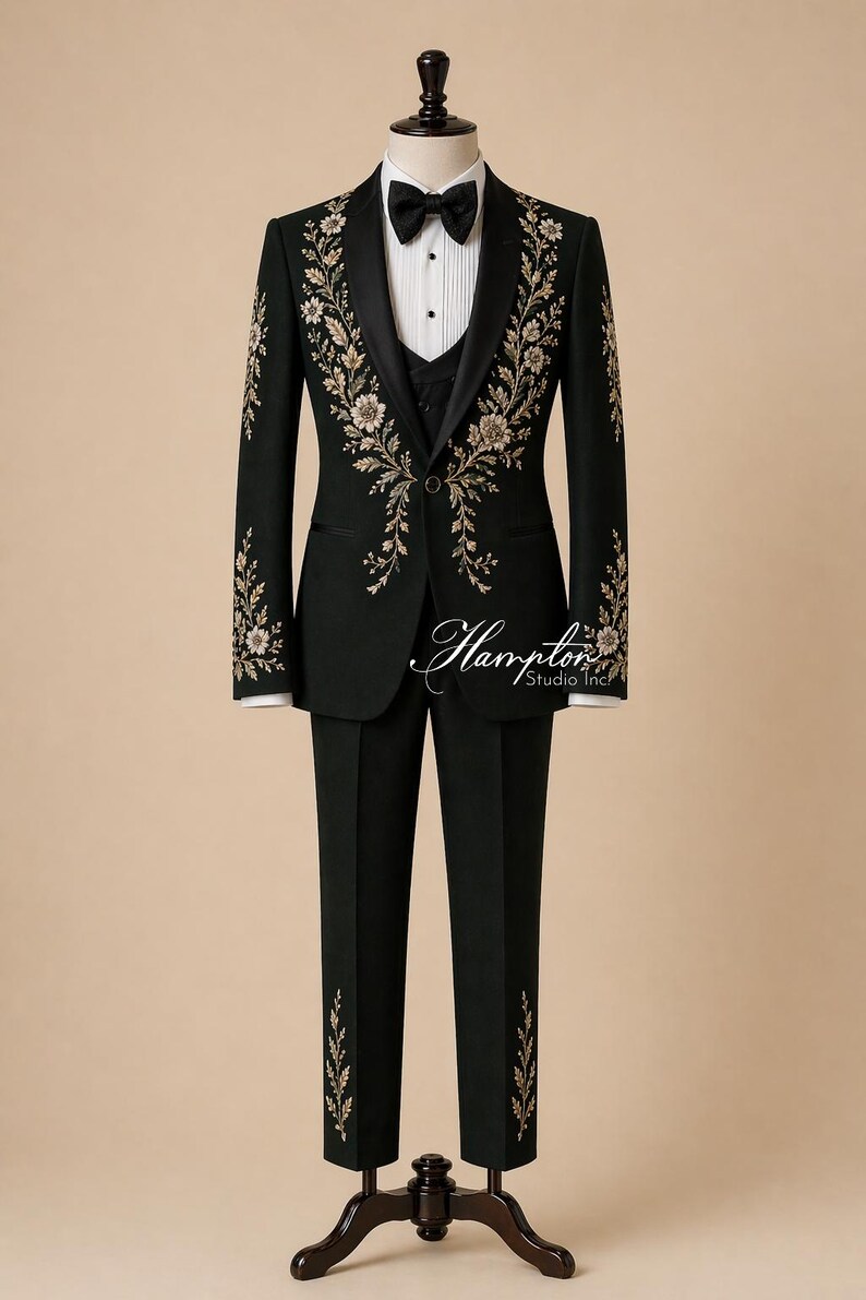 May include: A dark green formal suit with floral embroidery. The suit includes a blazer, vest, and trousers, displayed on a mannequin. The blazer features black lapels, a black bow tie, and white shirt. The floral embroidery is gold and cream-colored. The text "Hampton Studio Inc" is visible.
