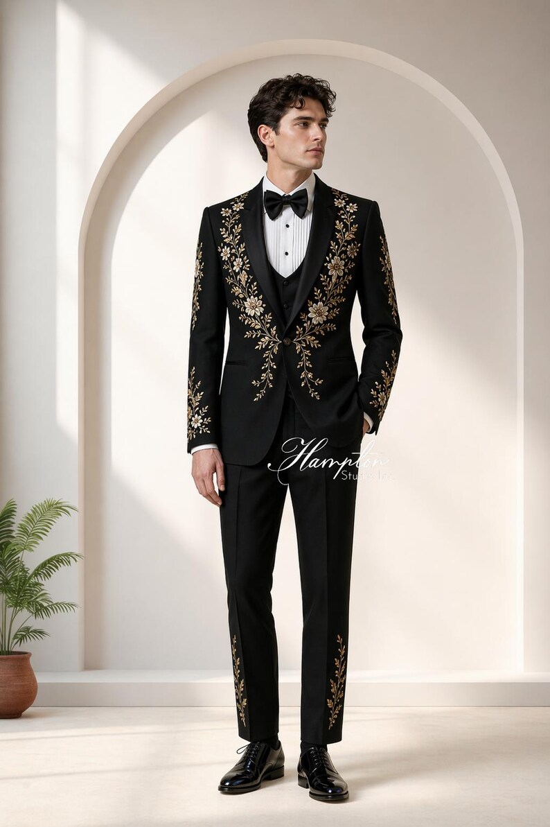 May include: Black tuxedo with gold floral embroidery. The suit includes a jacket, vest, and trousers. The jacket features ornate gold floral designs on the lapels and sleeves. The trousers have matching floral accents. A black bow tie completes the formal ensemble.