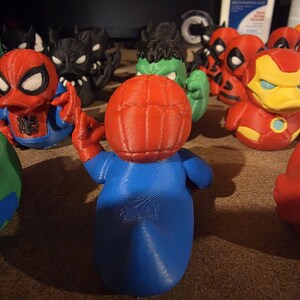 K&ouml;nnte beinhalten: Eine Sammlung von 3D-gedruckten Superheldenfiguren, darunter Spider-Man, Hulk, Iron Man und Deadpool. Die Spider-Man-Figur befindet sich im Vordergrund, mit rotem Kopf und blauem K&ouml;rper. Weitere Figuren sind in verschiedenen Farben.