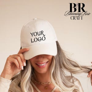 May include: A cream-colored baseball cap featuring the black text YOUR LOGO printed on the front center. The cap has a structured crown and a curved brim. The top right corner of the image displays the black text BR Blooming Rose CRAFT.