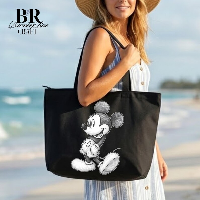May include: Black tote bag featuring a black and white illustration of Mickey Mouse. The bag has a zipper closure and black handles. The text "BR Blooming Rose Craft" is in the upper left corner. The bag is being held on a beach.