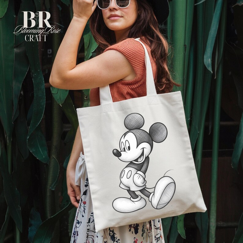May include: Cream-colored tote bag featuring a black and white illustration of Mickey Mouse. The bag has sturdy white handles and the text "BR Blooming Rose Craft" in the upper left corner. The bag is being held by a person.