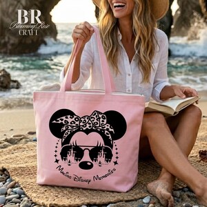 May include: A light pink tote bag with a black Minnie Mouse graphic, wearing sunglasses and a leopard print bow. The text "Making Disney Memories" is below the graphic. The bag has pink handles and a zipper closure.