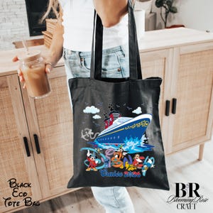May include: A black tote bag featuring a graphic of a blue and white cruise ship on water, surrounded by Disney characters including Mickey Mouse, Stitch, Goofy, Pluto, and Donald Duck, with the text Cruise 2026 printed in blue and red.