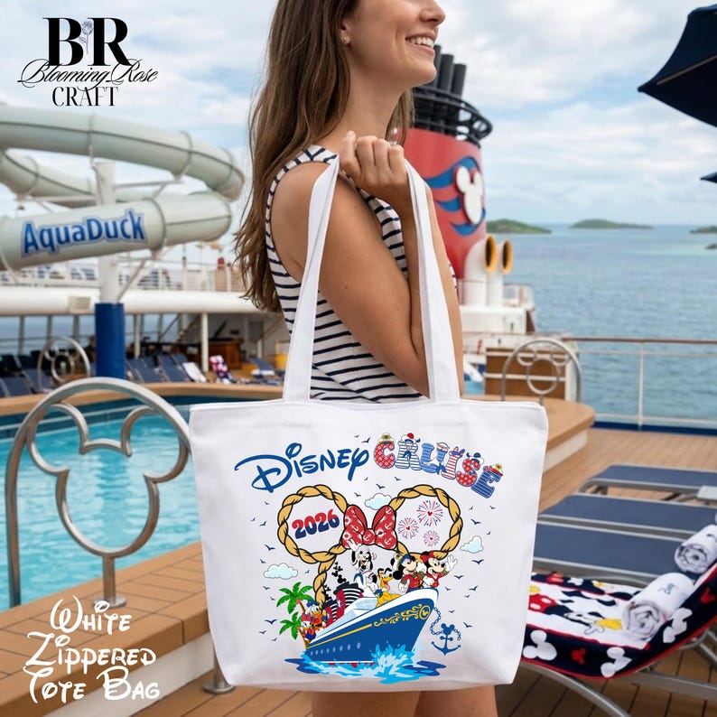 May include: A white tote bag featuring a graphic of a cruise ship with Disney characters, the text Disney Cruise, and the year 2026. The design includes rope-style Mickey Mouse ears, palm trees, and fireworks. The bag has two shoulder straps.