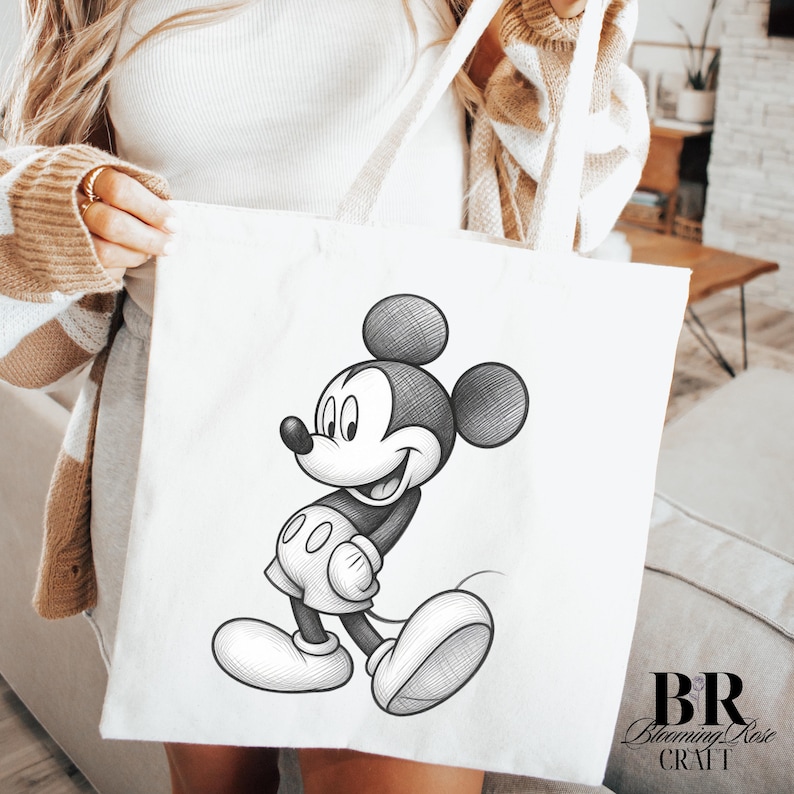 May include: White tote bag featuring a black and white sketch of Mickey Mouse. The illustration shows Mickey Mouse in a walking pose, smiling. The bag has long white handles and the text "BR Blooming Rose Craft" in the bottom right corner.