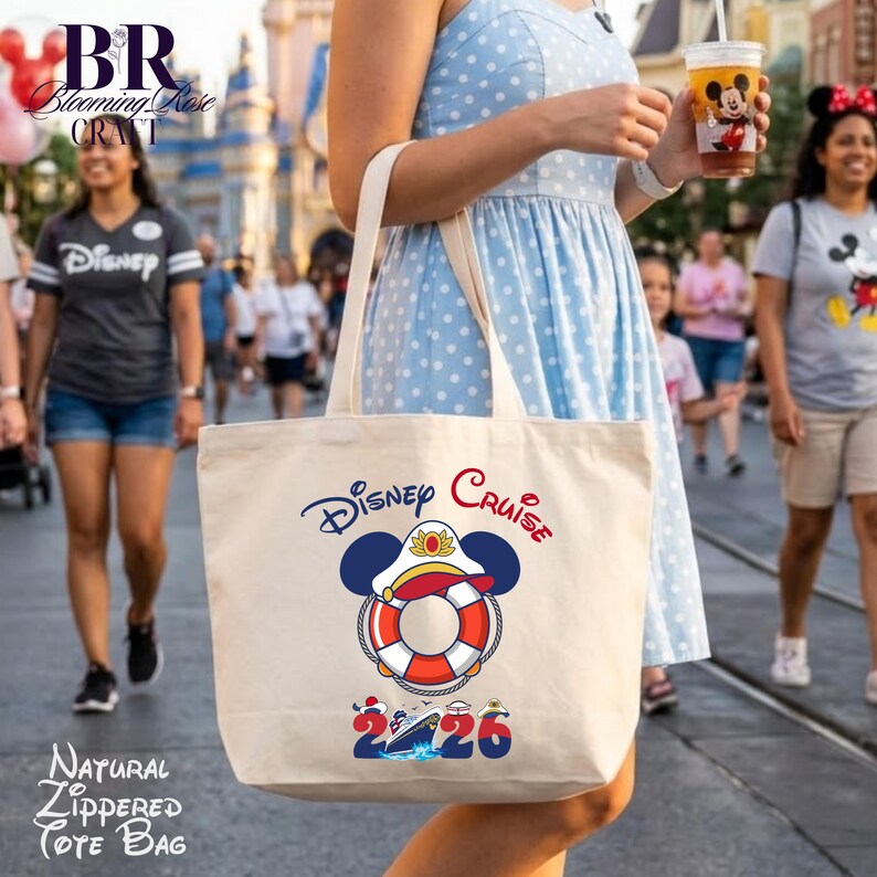 Puede incluir: Un bolso de tela de color natural con un gr&aacute;fico de un salvavidas que lleva una gorra de capit&aacute;n con orejas de Mickey Mouse. El texto dice Disney Cruise 2026, con una peque&ntilde;a ilustraci&oacute;n de un crucero integrada en el n&uacute;mero cero.