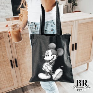 May include: Black tote bag featuring a detailed sketch of Mickey Mouse. The bag has a rectangular shape with two handles. The design is in black and white, with the Blooming Rose Craft logo in the bottom right corner.