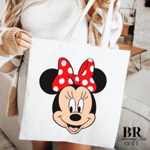 Puede incluir: Bolso tote blanco con la cara sonriente de Minnie Mouse, un lazo rojo con lunares blancos, orejas negras y una cara sonriente. El logotipo de Blooming Rose Craft est&aacute; en la esquina inferior derecha.