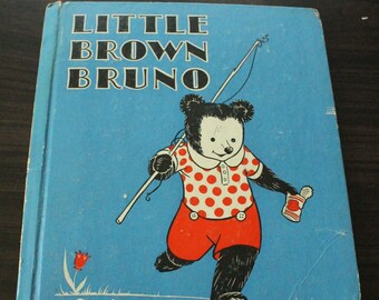 May include: A vintage children's book cover featuring a cartoon illustration of a brown bear with red polka dot shirt and red shorts holding a fishing rod and a can. The book title is "Little Brown Bruno" in blue letters.