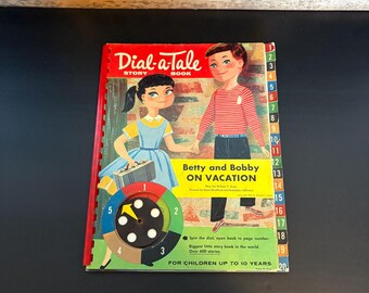 May include: A vintage "Dial-a-Tale" storybook titled "Betty and Bobby on Vacation." The cover features illustrations of two children and a spinning dial. The book is red with a colorful design and is for children up to 10 years old.