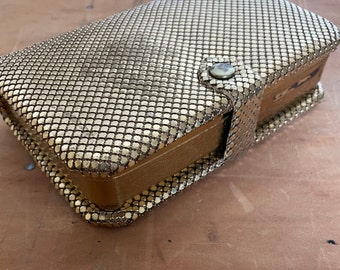 May include: A gold mesh jewelry box with a hinged lid and a snap closure. The box is made of a fine mesh material and has a vintage look.