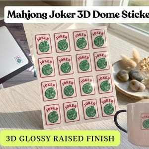 May include: A sheet of 3D dome stickers with a glossy raised finish, featuring a Mahjong Joker design. The stickers are displayed next to a matching mug and a laptop with a sticker on it. The text "Mahjong Joker 3D Dome Stickers" is at the top.